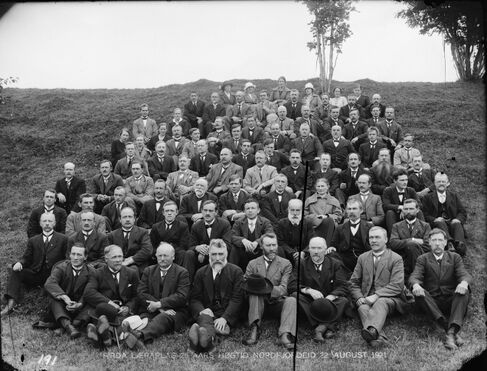 Svart-kvitt foto av ei stor gruppe lærarar, kring 80 stykker. Dei sitt på ein gressbakke. Dei fleste er menn med dress og slips - nokre held hattar i hendene. Det er også nokre kvinner litt lenger bak i gruppa. Tre damer bakerst har hatt på hovudet.