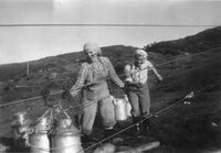 Aslaug Berge og Solbjørg Berge sender mjølkespann ned taubana. Mjølkespanna måtte dras ned forbi første bukken. Rundt 1960.
