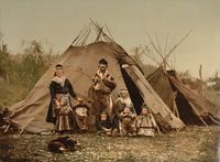 Samisk familie utenfor en kåte. På bildet ser vi også en komse. Ukjent fotograf, ca. 1900