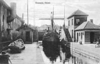 Postkort med motiv Skien sluse som løfter i et kammer opp fem meter fra Skienselva (Bryggevannet) til Hjellevannet. Foto: Telemark Museum