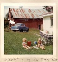 Låven og hjørnet av våningshuset, sett mot vest. Solfrid og Heidi Grønnerud sitter på bakken, mens Anne Grønnerud er i barnevogna. Foto: Solveig Grønnerud, sommeren 1968
