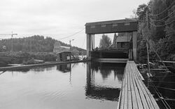Innløpet, sett fra flåtegangen som utgjorde den vestre påstikkingslensa. Kraftstasjonsbygningen i bakgrunnen. Foto: Ole-Thorstein Ljøstad/Anno Norsk Skogmuseum (1985).
