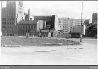Den daværende Triangelplassen hvor arbeidere i gang med å utforme et langsmalt grøntområde. Fra venstre Torstedgården (1935), Stortingsgata 30, Ruseløkkveien 6B (dengang) og de opprinnelige bygningene fra Thunes mekaniske verksted i Ruseløkkveien 8-10, hvor Kommunenes hus ble oppført 1956/1957. Foto: Oslo byarkiv (1935-1956).