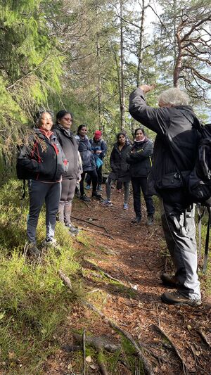 Aktive Kvinner i Bjerke på tur med Håvard Pedersen fra Lillomarkas Venner. Håvard tok seg tid til å vise mange kjerneområder av Lillomarka med historien til vår vakre skog. Alle står rundt Håvard når han forteller om historien til Lillomarka blant trærne til den vakre skogen.
